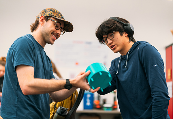 Two students working with a 3D printed object in a lab