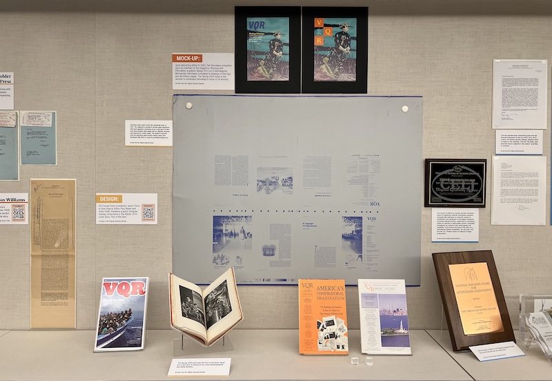 An exhibition display case. The backdrop features a large diagram and several smaller text exhibits on a wall.